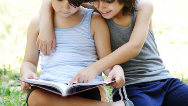 Little two boys reading a book in garden