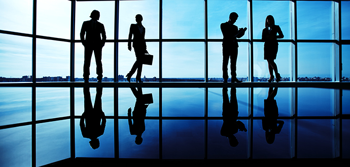 Silhouettes of several office workers standing on background of window